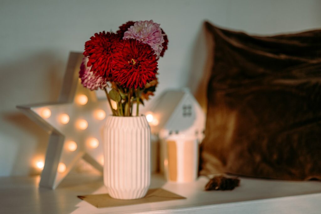 White vase with red and pink flowers on shelf