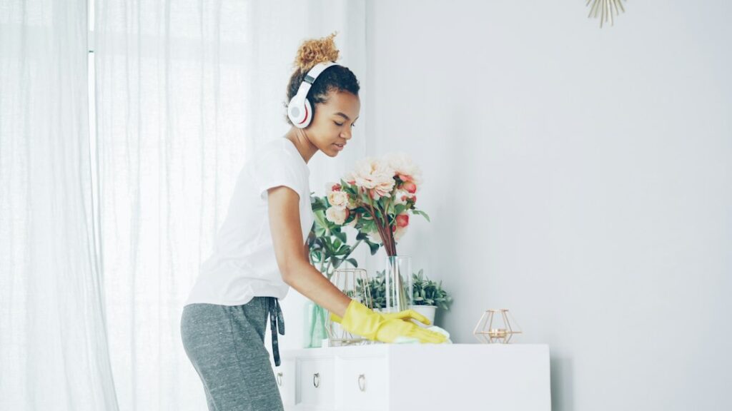 Woman with headphones cleaning a shelf